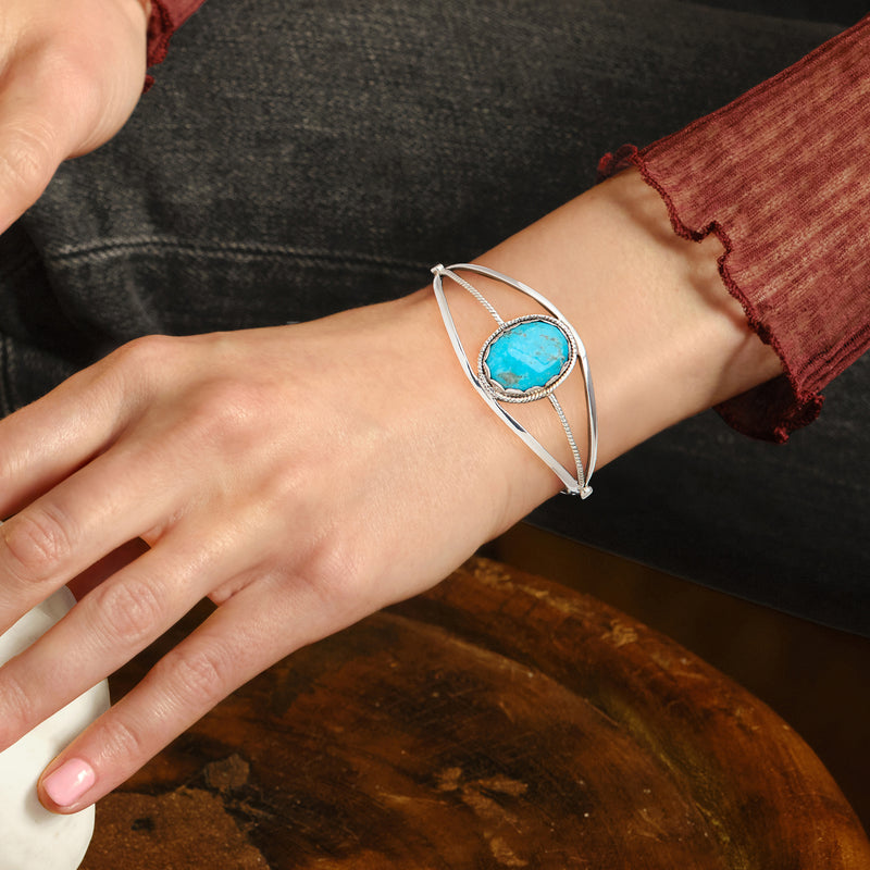 Turquoise stone sterling silver cuff bracelet on wrist, oval bezel with braided accents