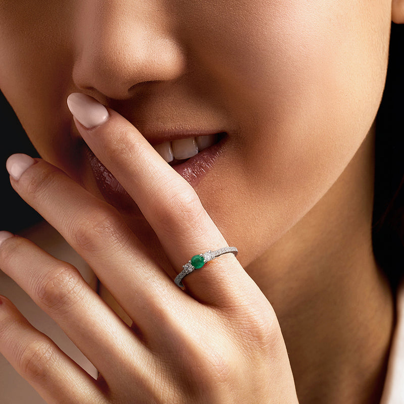 Platinum ring with green center stone and diamond band on hand