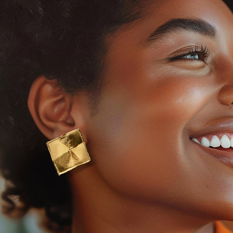 Square gold-tone stud earrings on model, brushed textured finish