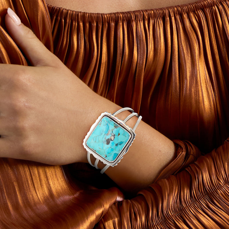 Square turquoise cuff bracelet in sterling silver worn on wrist with white band accents