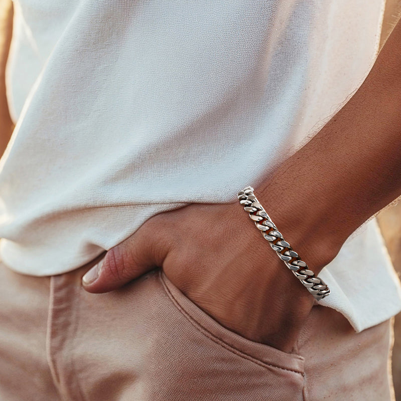 Stainless steel Cuban-link bracelet on wrist; polished links with secure clasp