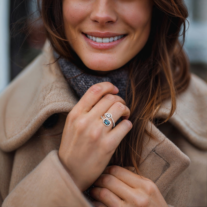 Sterling silver ring with blue topaz center and diamond halo, worn on finger