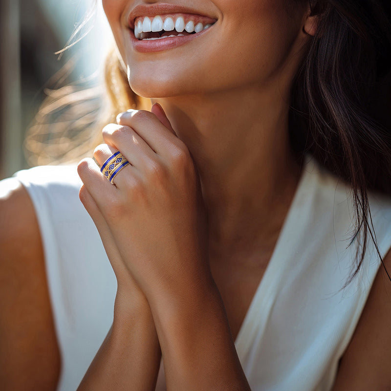 Gold-tone stackable rings with blue enamel on fingertip, worn by person