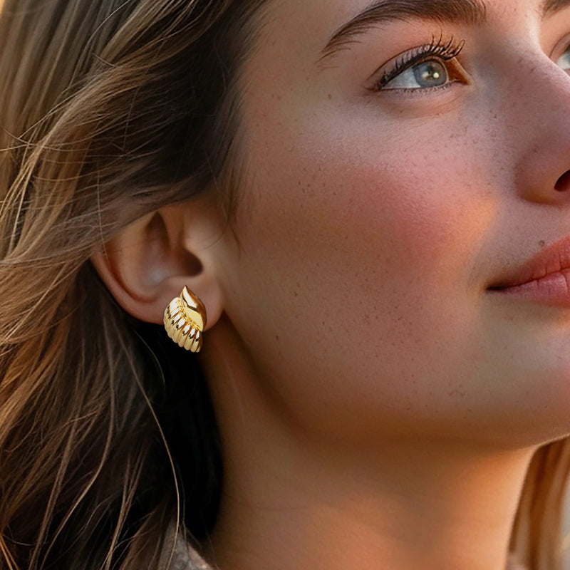 Gold seashell stud earrings, ribbed scallop design on a model