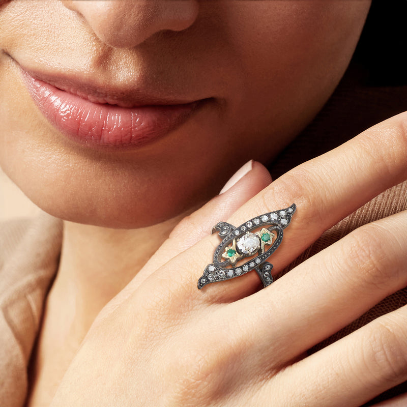 Marquise diamond and emerald ring on hand, blackened silver frame with yellow gold base