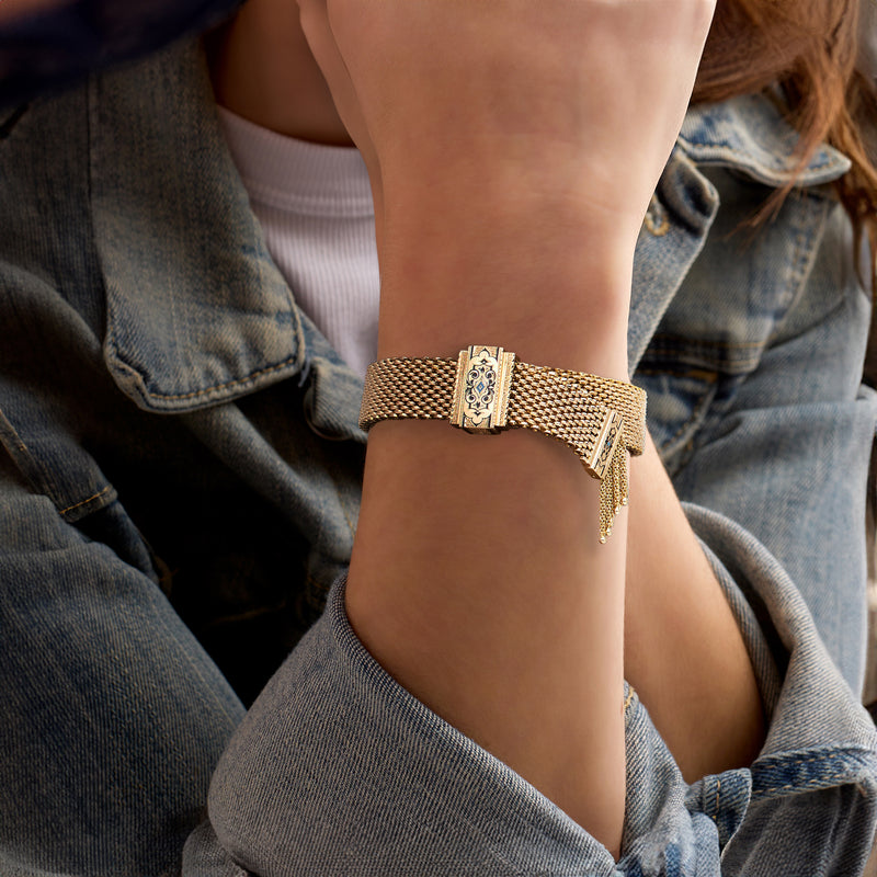 Gold mesh tassel bracelet with enamel panel and dangling end fringe on wrist