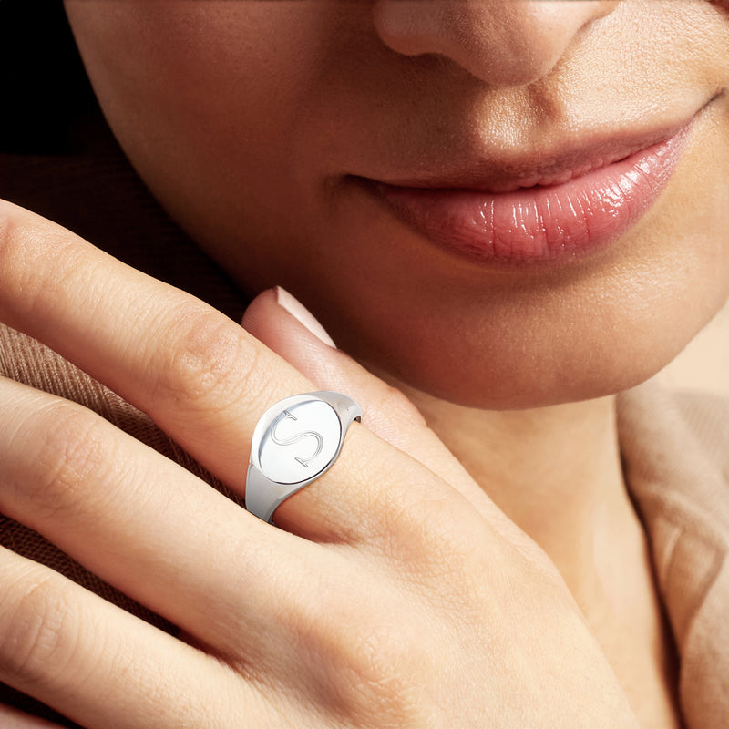 Oval sterling silver monogram signet ring on finger, close-up