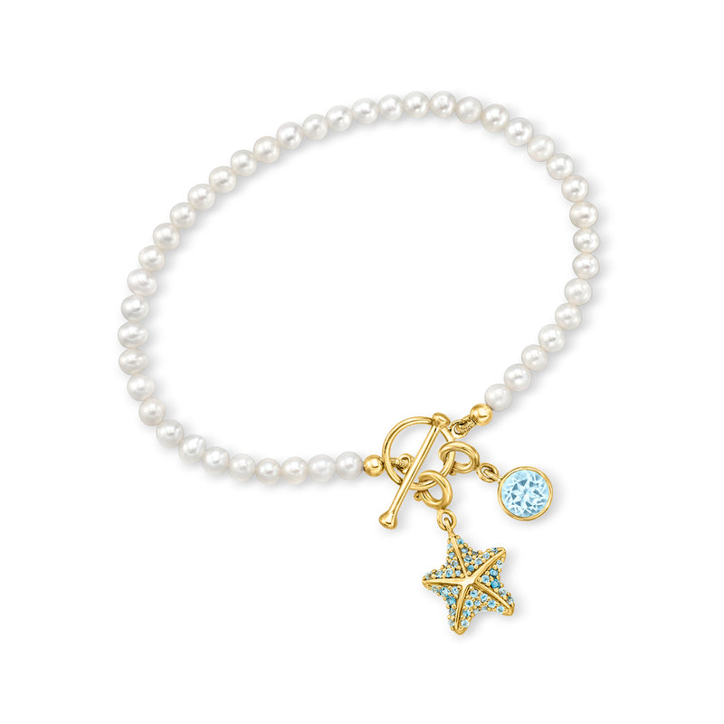 Cultured pearl toggle bracelet with gold charms, blue round stone, and star charm