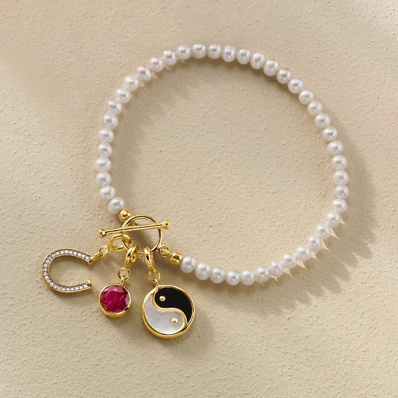 Cultured pearl bracelet with gold toggle and charms: letter C, red drop, and yin-yang