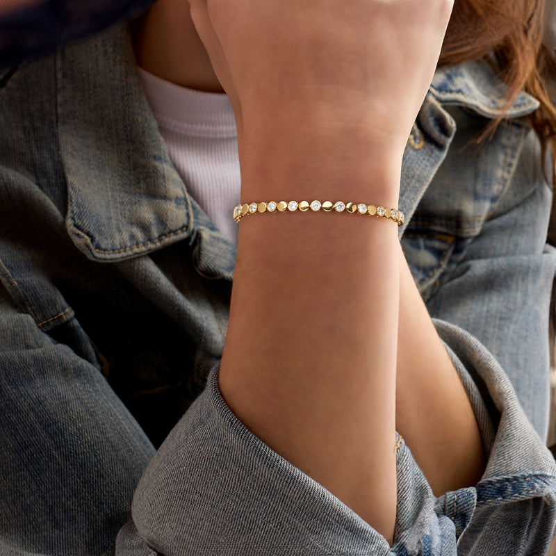 Gold bracelet with alternating round diamond discs worn on wrist