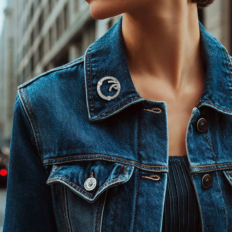 Round platinum diamond circle pin on a blue denim jacket collar