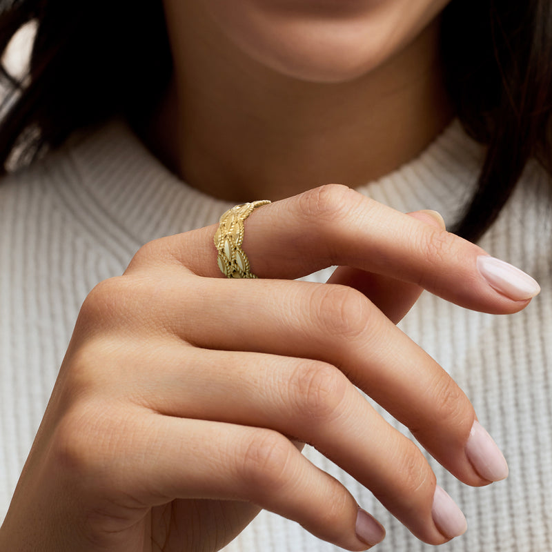 Gold roped ring on finger with textured oval link band