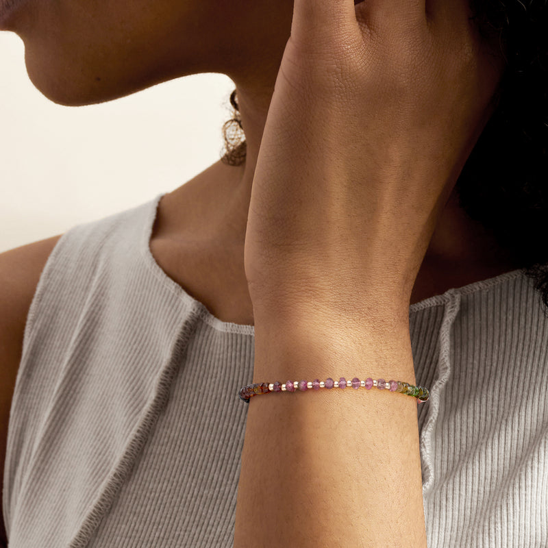 Multicolored tourmaline bead bracelet on wrist with thin gold clasp and extender