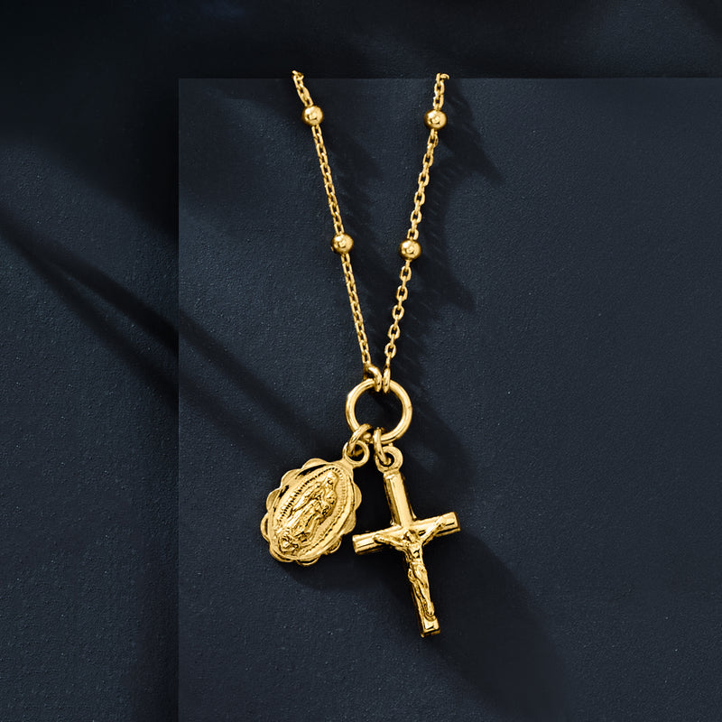 Gold-tone chain necklace with circular medallion and cross charm, dangling