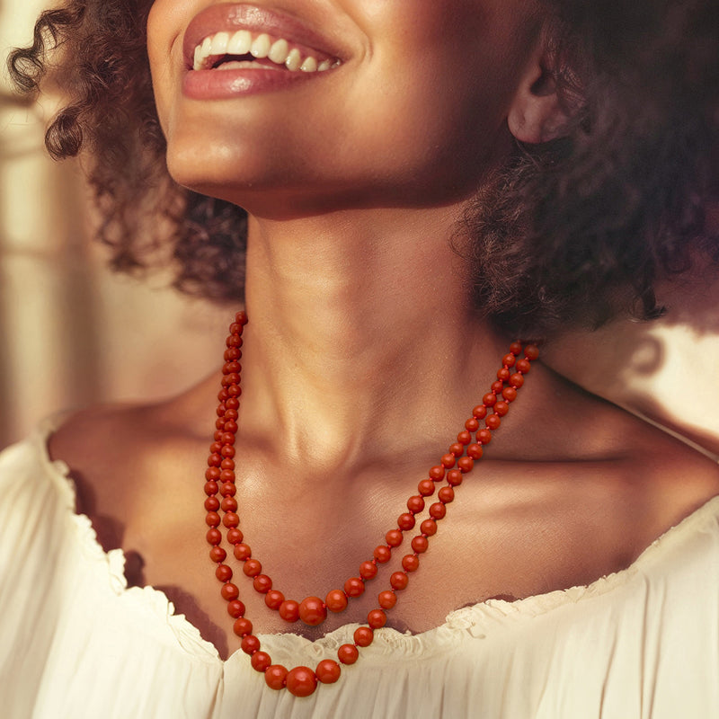 Two-row coral bead necklace worn with ivory scoop-neck top