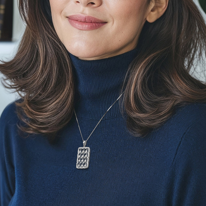 Diamond grid pendant necklace worn on a fine chain; rectangular pendant with round stones