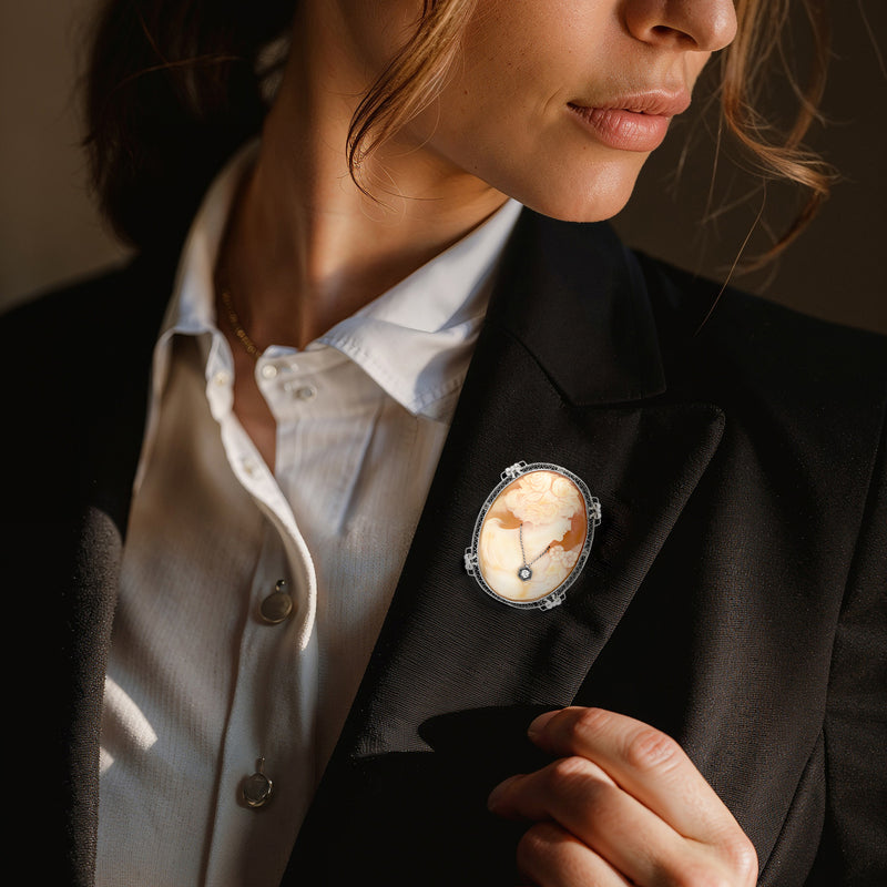 Oval shell cameo pin in white gold with portrait profile and dark diamond on lapel