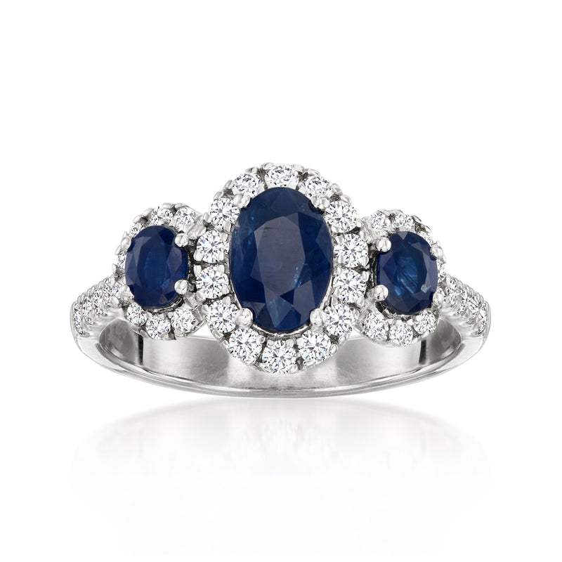 Platinum three-stone ring with oval blue sapphire center and diamond halo sides