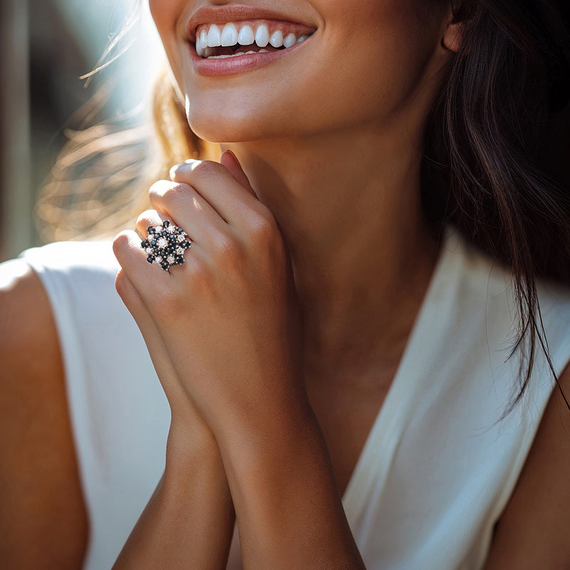 Blue and white diamond cluster ring on finger, white gold band