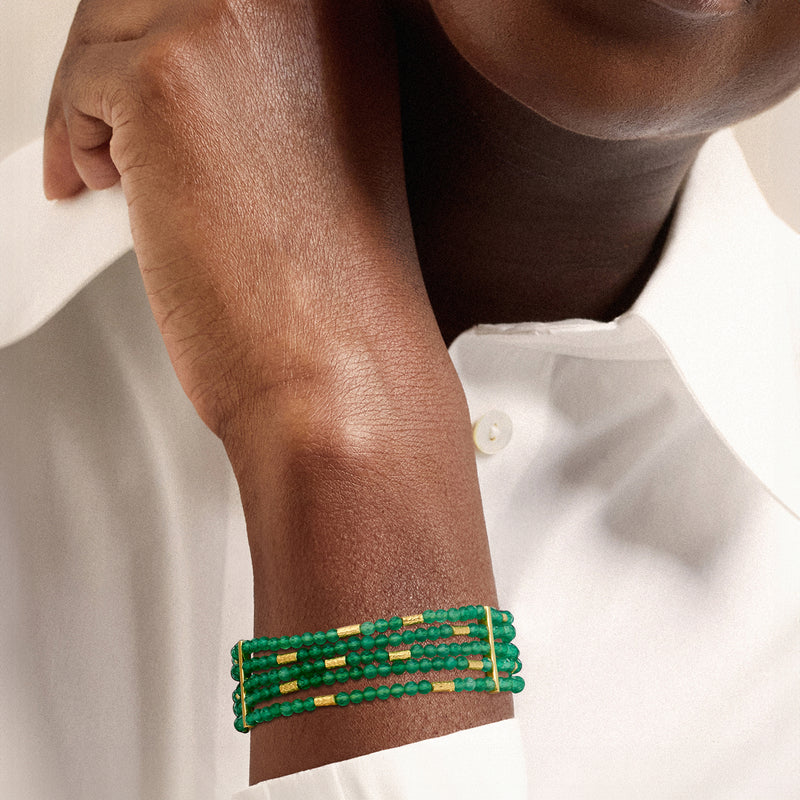Green five-row bead bracelet on wrist with gold clasp