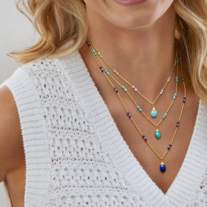 Gold-tone layered necklace on model with blue, turquoise, and dark beads