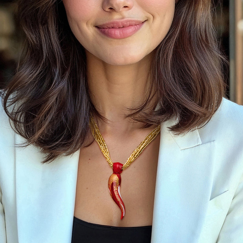 Red horn pendant necklace with layered gold multi-strand chain, on neckline