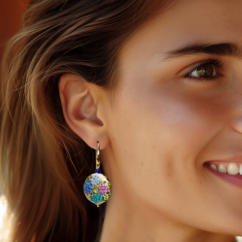 Murano glass drop earrings on ear: multicolored round disc with blue bead, gold earwire