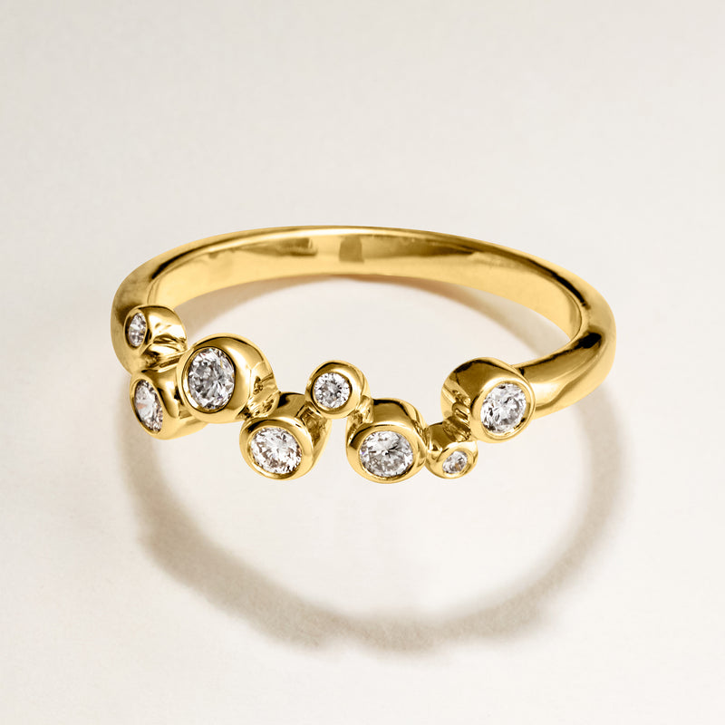 Gold zigzag diamond ring with round bezel-set stones across the top
