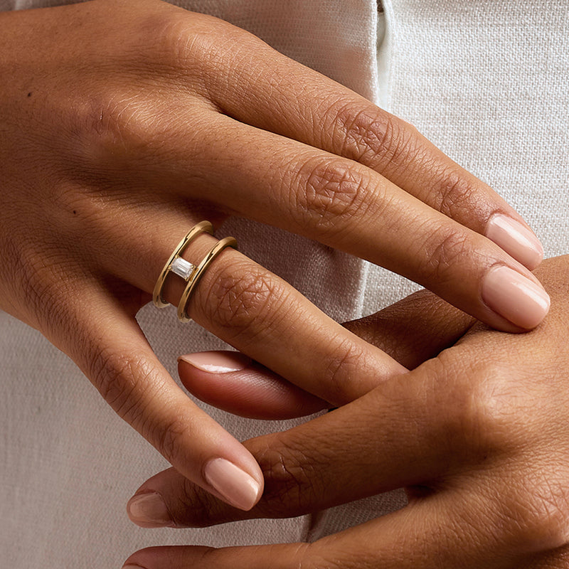 Gold open-space ring on hand with emerald-cut diamond centerpiece in split bands