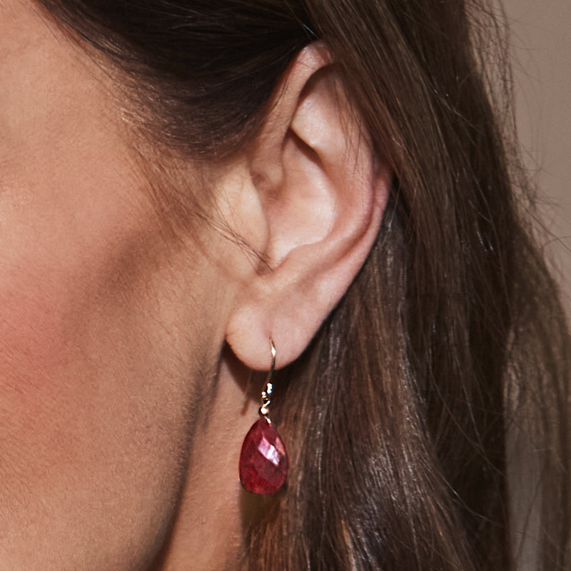 Yellow gold earwire drop earrings with faceted red teardrop ruby, close-up