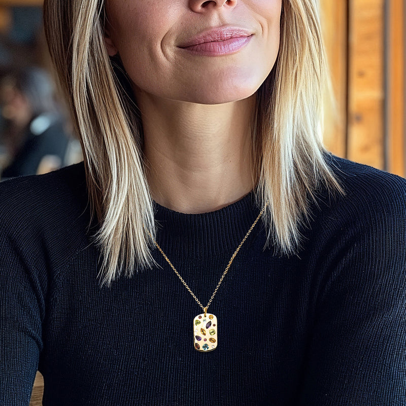 Gold tag pendant necklace on model, multicolor gemstones on dark outfit