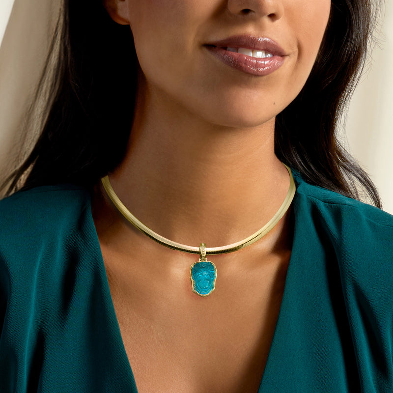 Gold choker necklace with small blue glass face enhancer pendant at center
