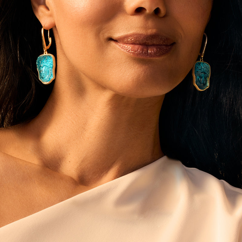 Gold leverback drop earrings with blue glass face pendants, framed in gold