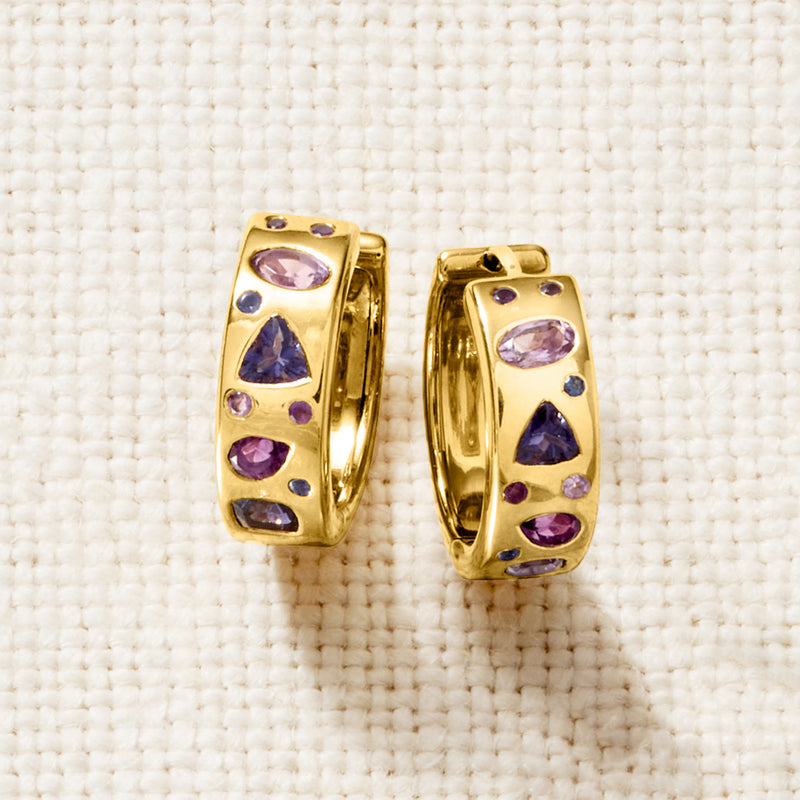 Gold-tone hoop earrings, close-up, with multiple purple oval gemstones on the band