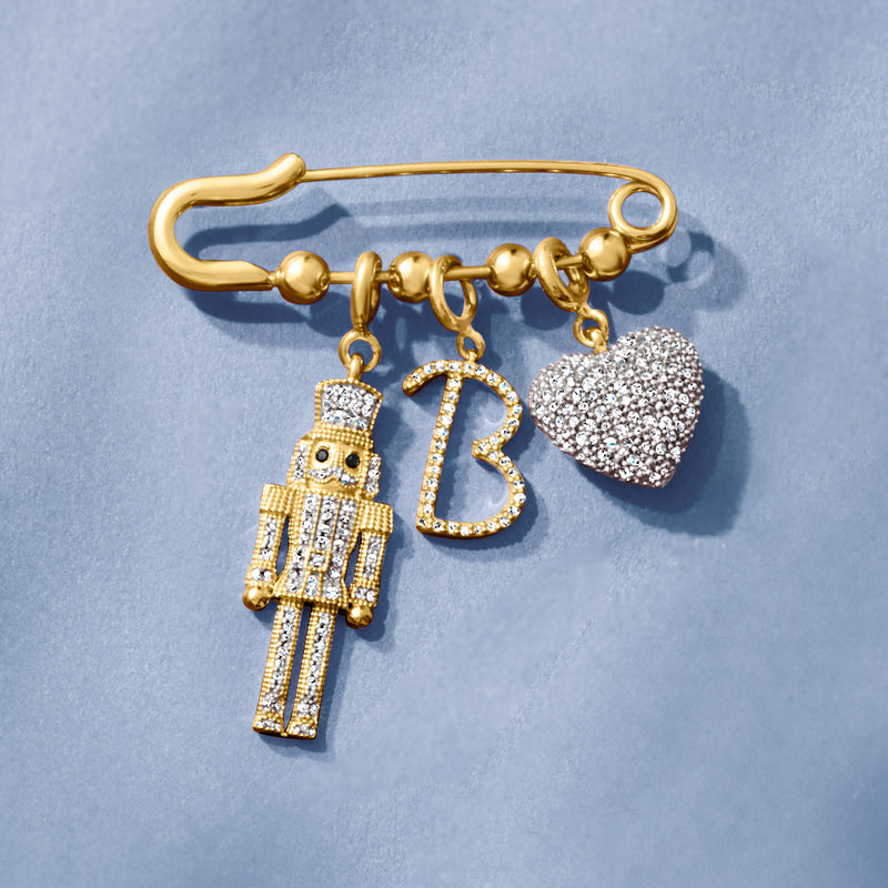 Gold-tone safety pin with letter B, nutcracker charm, and sparkling heart charm