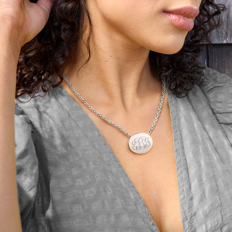 Silver oval monogram pendant necklace with chain worn at neckline
