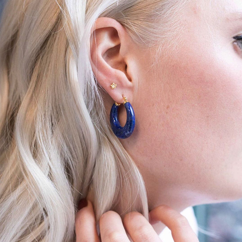 Blue lapis hoop earrings with 14kt yellow gold studs on top, worn on ear