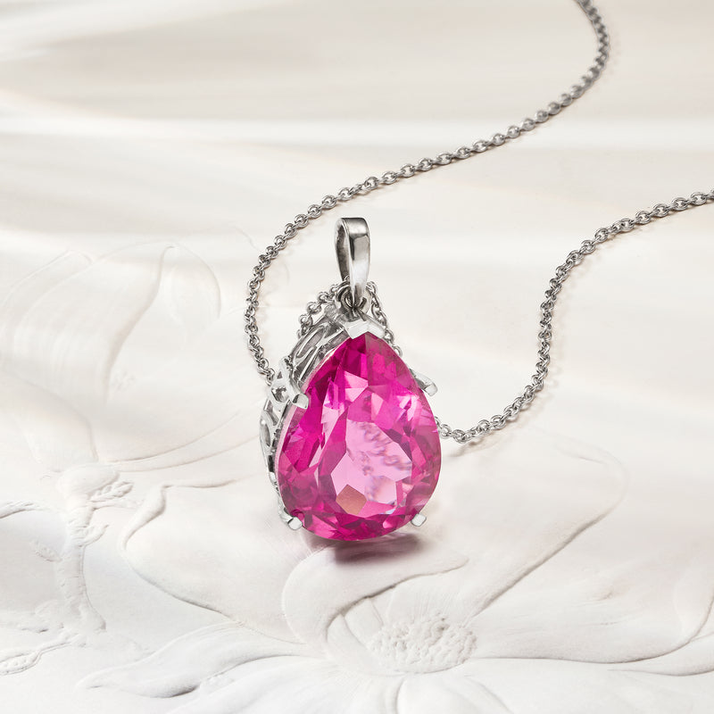 Sterling silver pink topaz teardrop pendant necklace, shown resting on fabric