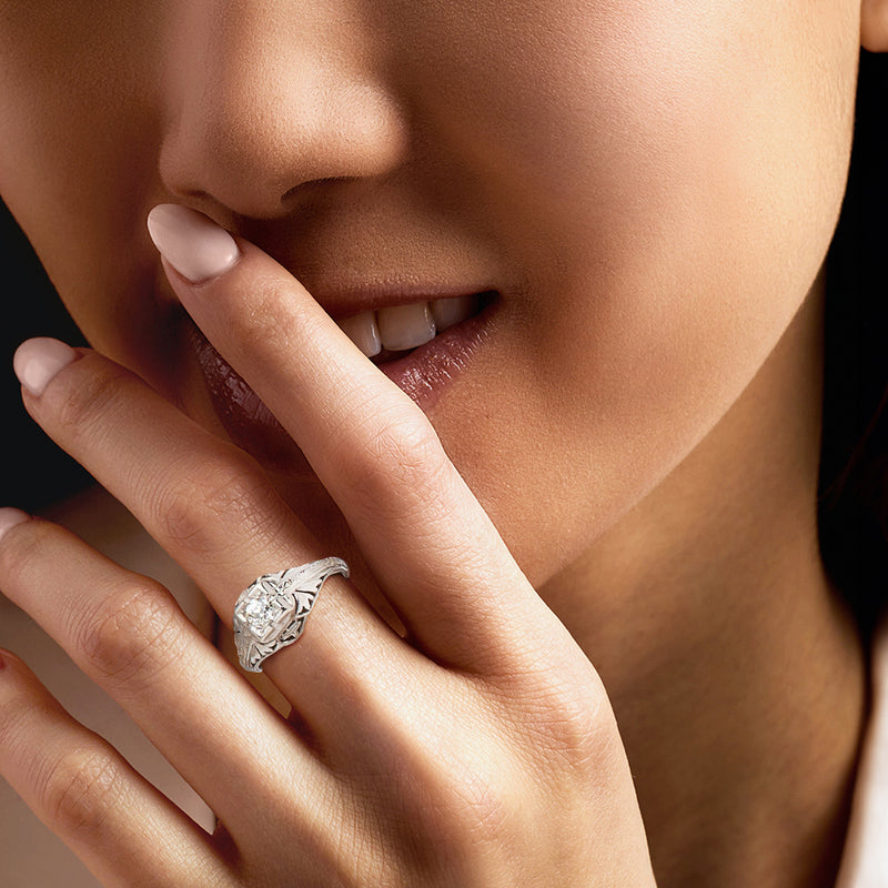 Platinum vintage diamond ring on finger, round center stone with detailed engraved band