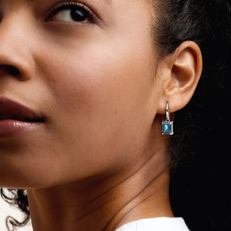 Square blue topaz drop earring on ear, sterling silver leverback