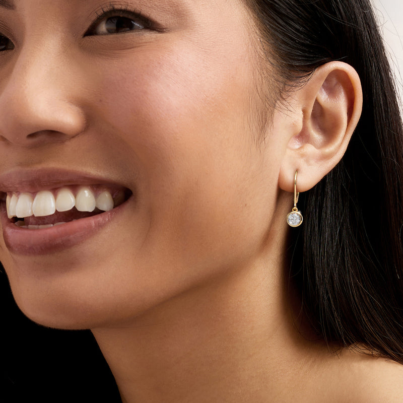 Gold drop earrings with round diamond and leverback closure on ear
