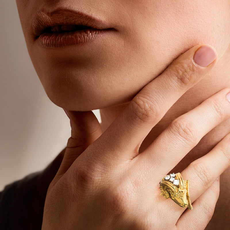 Ram head diamond ring in 18kt yellow gold worn on finger with round stones