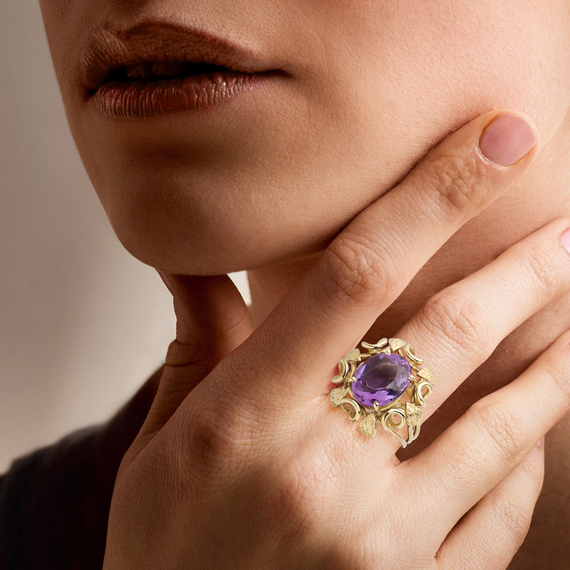 Amethyst oval ring in 18kt yellow gold worn on finger with filigree detail
