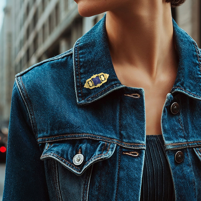 Lapis bar pin on blue denim jacket collar; blue stone set in yellow gold frame.
