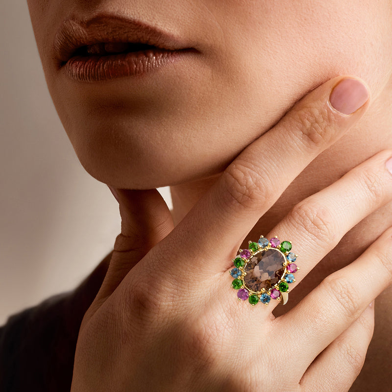 Multi-gemstone ring on finger with smoky quartz center and colorful gemstone halo