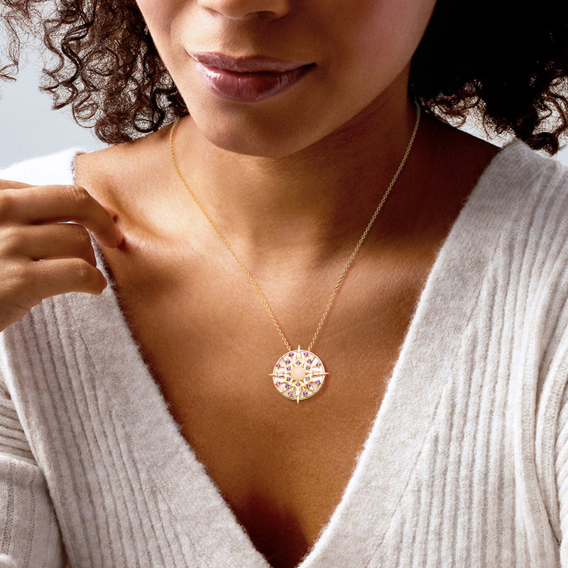 Gold compass pendant necklace worn on model, opal center with purple gemstone ring