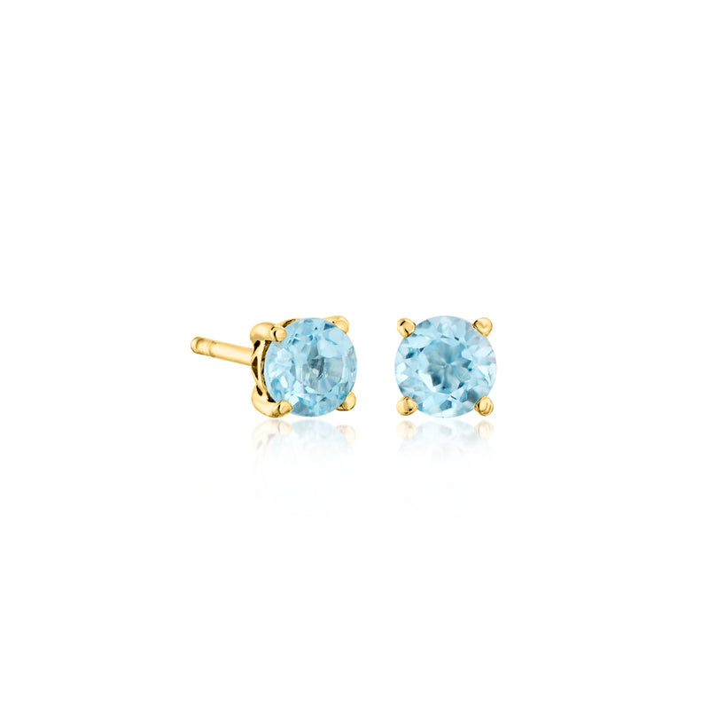 Gold-tone round gemstone stud earrings pair with light blue stones and prong settings