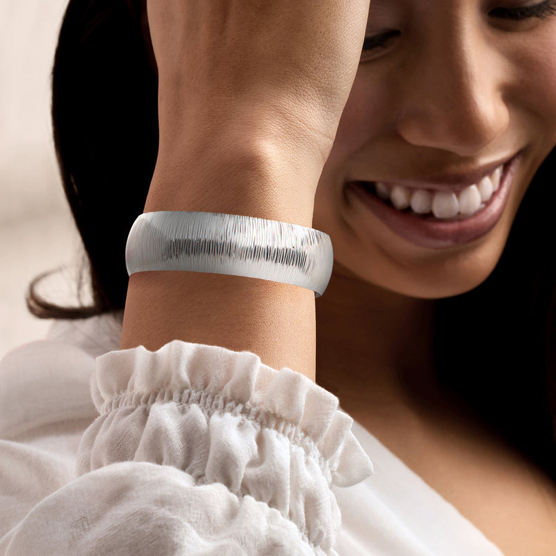 Sterling silver textured cuff bracelet worn on wrist, wide band