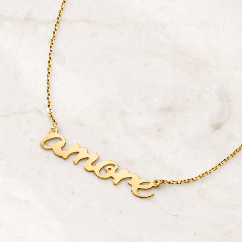 Close-up of 14kt yellow gold “amore” cursive pendant on chain