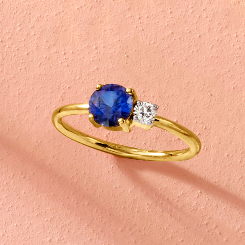 Gold ring with oval blue sapphire and one round diamond accent on a slim band